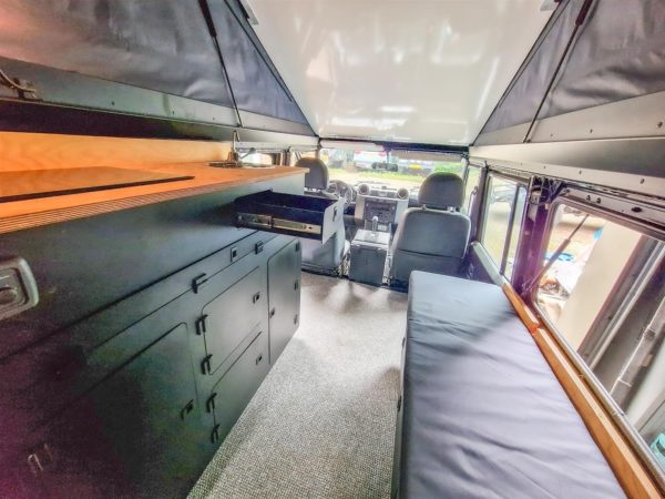 Komplettes Camper-Interieur in einem Land Rover Defender 110: Küchenschrank, Sitzbank und Querschrank