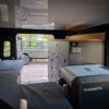 Camper-Interieur Defender 110 in Gebrauch mit ausgeklapptem Bett und Kühlbox
