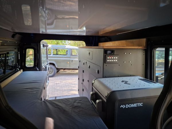 Camper-Interieur Defender 110 in Gebrauch mit ausgeklapptem Bett und Kühlbox