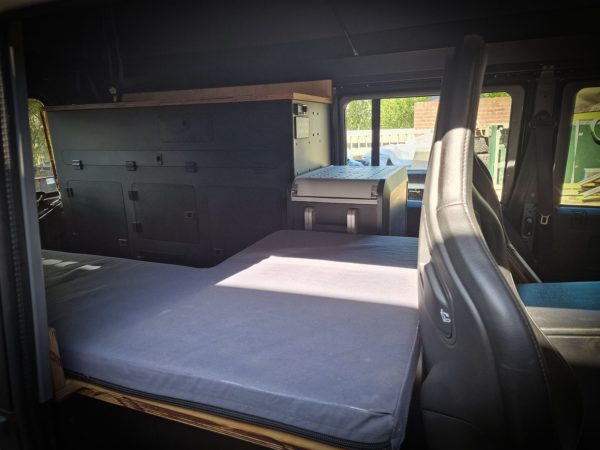 Niedriger Seitenschrank als Sitzbank und Schlafplatz in einem Land Rover Defender 110