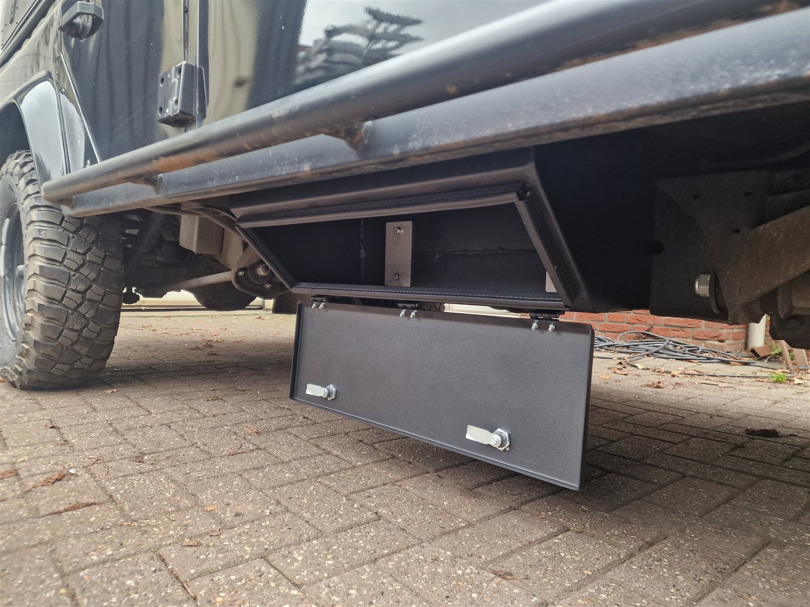 Chassis storage box mounted open under a Land Rover Defender